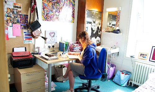 A student sat at a desk in University halls of residence.