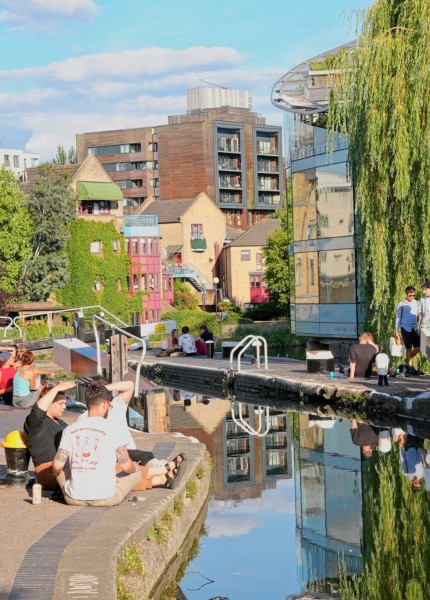 People sat around a canal going through Manchester city centre.