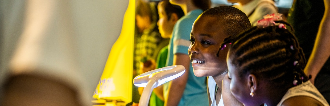 Two smiling children enjoy table-top science activities.