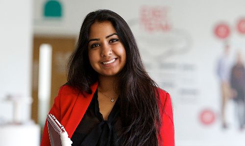 Female student holding books and smiling into camera.