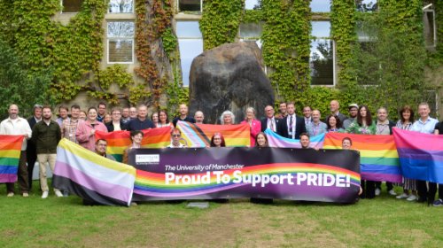 University colleagues photographed holding banners and flags to indicate their support for Manchester Pride and the LGBTQ community.