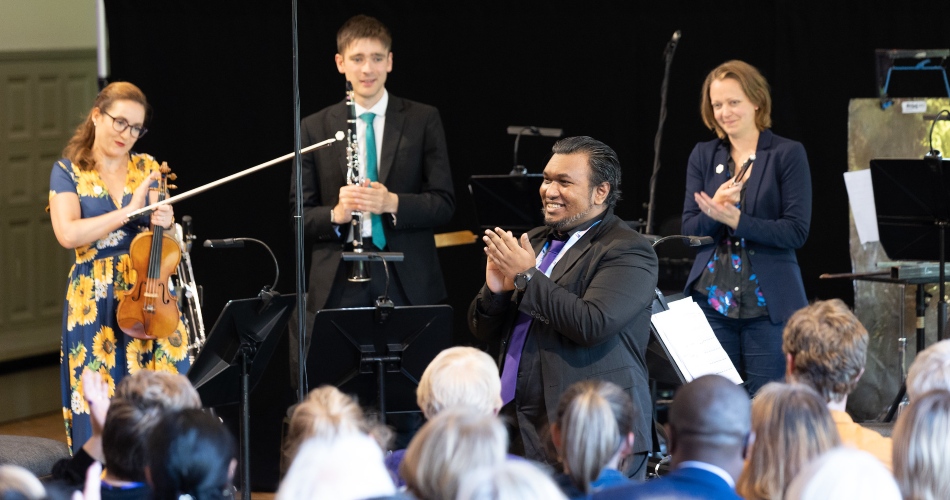 The crowd applauds musicians and composer.
