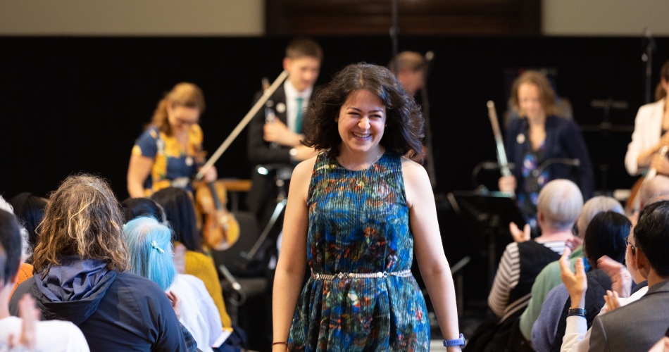 A performer smiles to applause from the crowd.