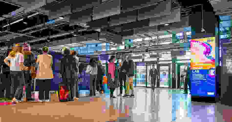A crowd gathers at the Ideas Lab pop-up exhibition, beside lightbox promotional messaging.