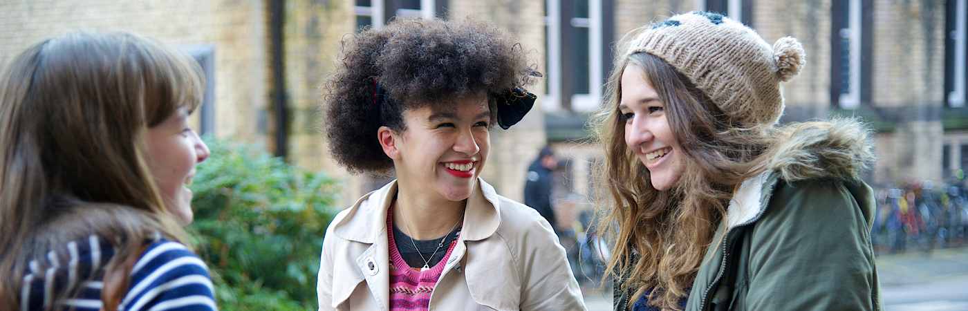 Three Manchester students smiling at each other