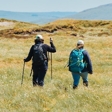 People walking across open moorland landscape.