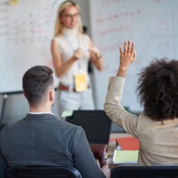Business lecture with woman raising hand to ask a question. 