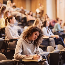 Woman studying, sat in a lecture theatre