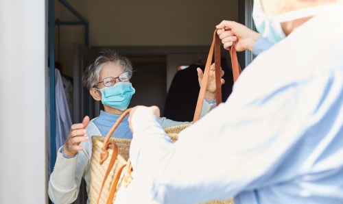 iStock image of shopping being delivered to an older person in a face mask.