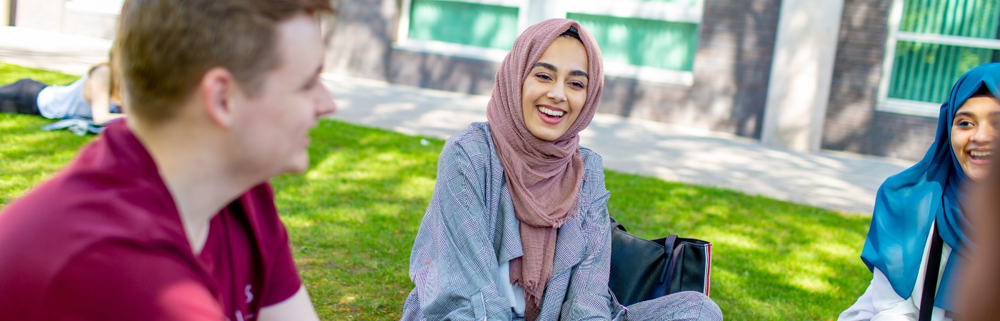 Students sat on the grass laughing 