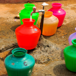 Colourful buckets under a tap.