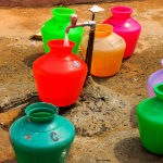 Colourful buckets under a tap.