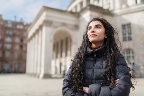 Student smiling, stood next to Central Library in Manchester