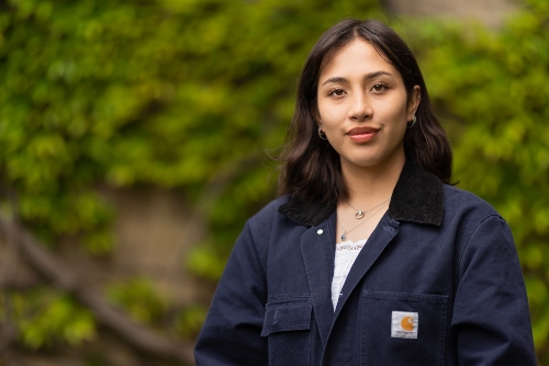 Student smiling stood against the Beyer Building, The University of Manchester 