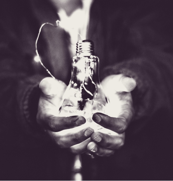 Black-and-white image of hands holding a lightbulb.