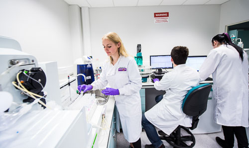 Scientists in white lab coats work in a lab.