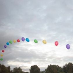 A park with a rainbow made out of balloons. 