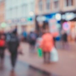 Blurred out people walking through a town centre. 