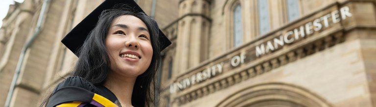 An alumnae stood underneath the iconic University of Manchester sign.