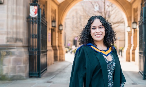 Graduate standing outside The University of Manchester 