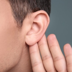 Man with hearing problem on grey background, closeup