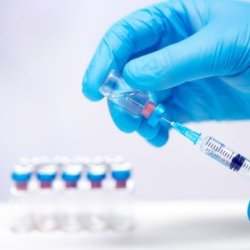 Scientist hand in blue gloves holding coronavirus, covid-19 vaccine disease, preparing for human clinical trials vaccination shot. 