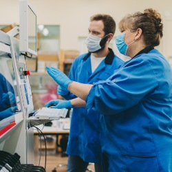 Two production factory workers wearing protective facemasks. Credit iStock/martin-dm