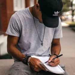 Young black man in baseball cap, writing on paper