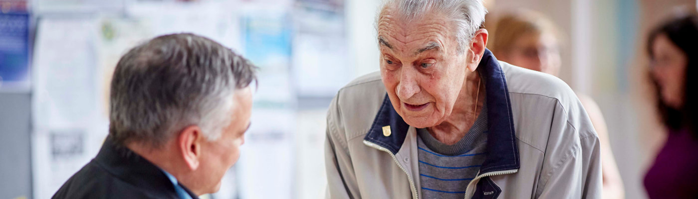 An older man talking to another older man