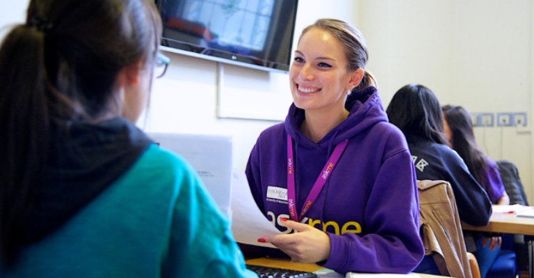 A University representative smiles and chats to a student.