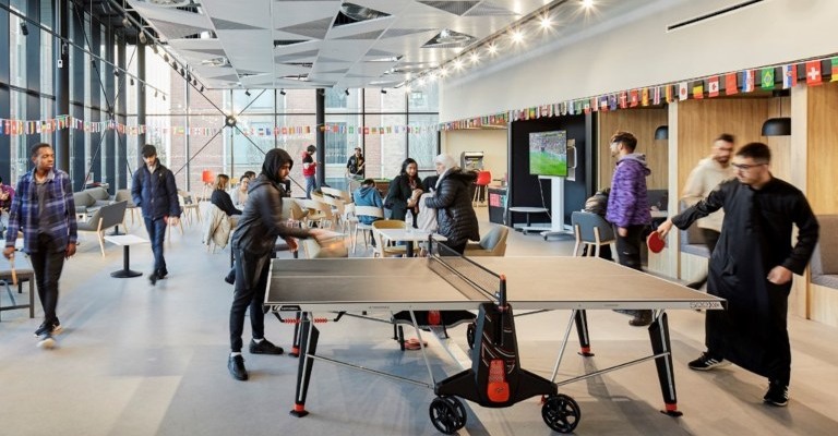 Students play table tennis and socialise in a modern accommodation social space.