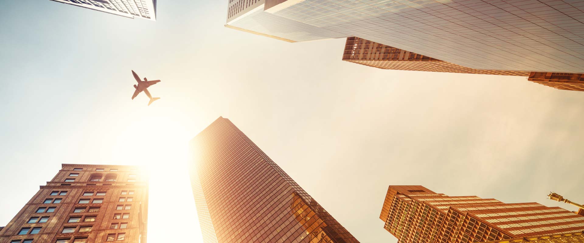 Skyscrapers with airplane flying across the sky