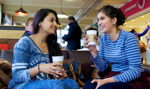 Two women chat and drink coffee in a cafe