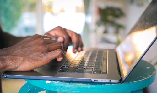 A pair of hands typing on a laptop.