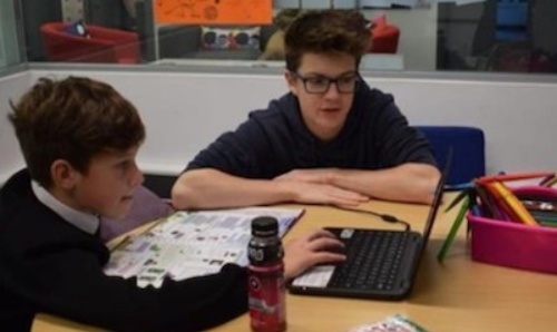 Student helping young person on computer