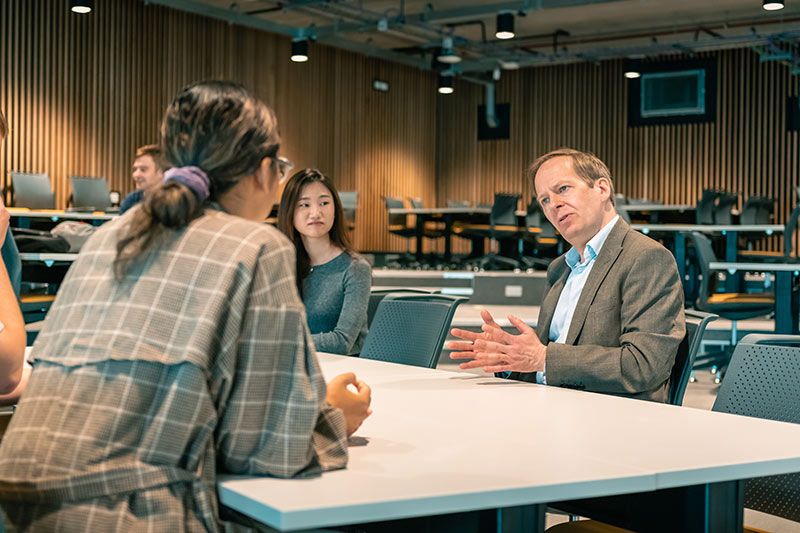 A teacher and student in discussion around a table.