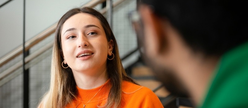 A student explains something to a fellow student on steps inside Engineering Building A.