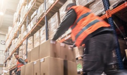 Two men pushing boxes in a warehouse
