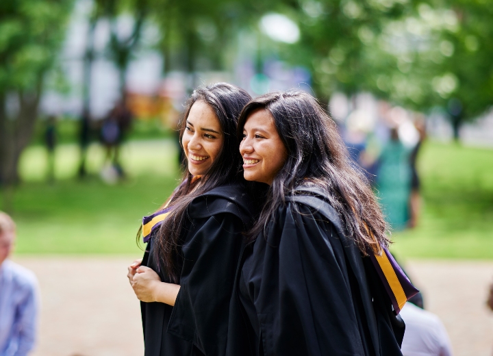 Two graduates smiling in their gowns