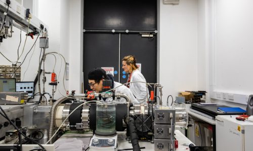 A male and a female researcher using mass spectrometry equipment in a laboratory setting.