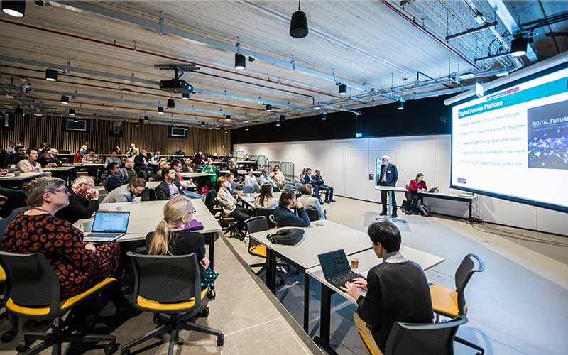 Audience in a modern lecture hall watching a presentation on the Digital Futures Platform.