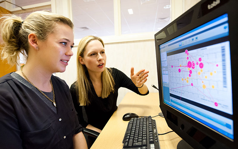 Two researchers discussing data visualisation on a computer screen, symbolising AI and innovation.