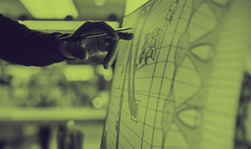 Hand holding a pen pointing at a technical design on a screen, symbolising research and innovation.