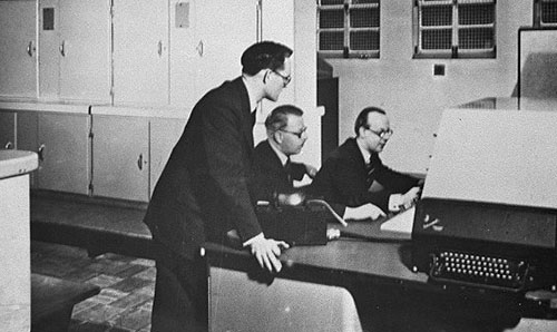 Three men, including Tom Kilburn, standing at the console of the Ferranti MK I.