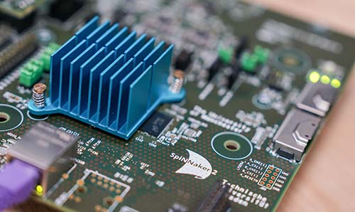 A close up of a mother board with the SpiNNaker 2 logo printed on it.