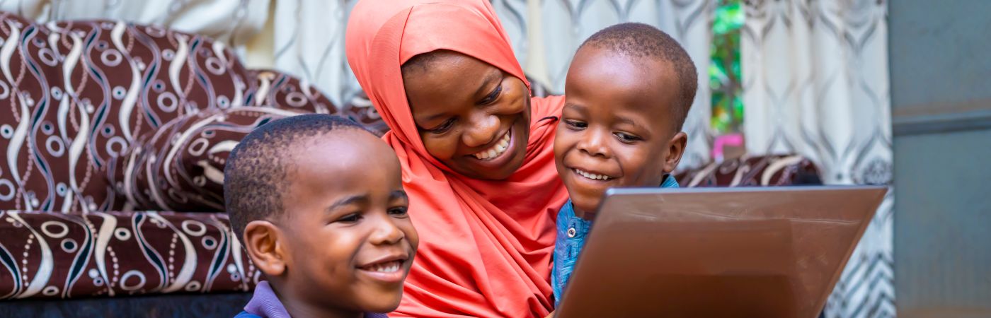 Black African mother with two little preschool sons sitting using computer (Shutterstock)