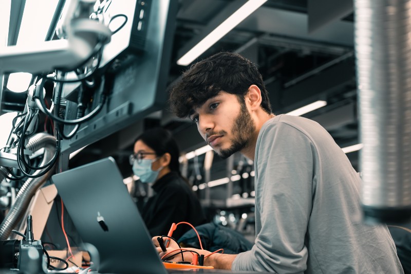 A student taking notes and looking at his computer screen.