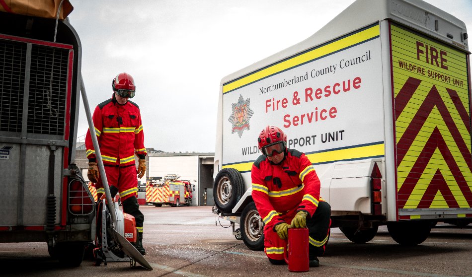 A group of people in a workshop meeting around a table with notebooks and pens in a studio space.