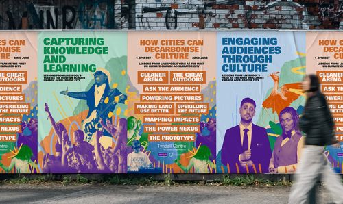 Person walking past posters on a wall promoting culture, learning and climate action.