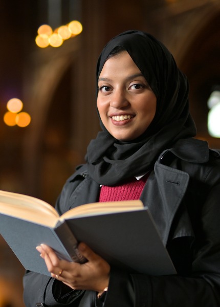 Student holding a book in John Rylands Library.